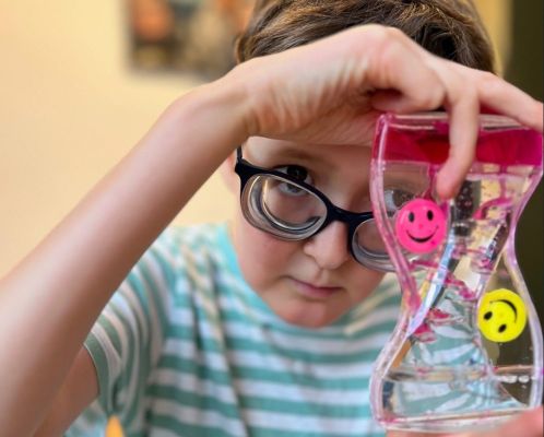 Sam, de zoon van Dessie, staat op de foto en kijkt naar een speeltje dat hij in zijn hand heeft.